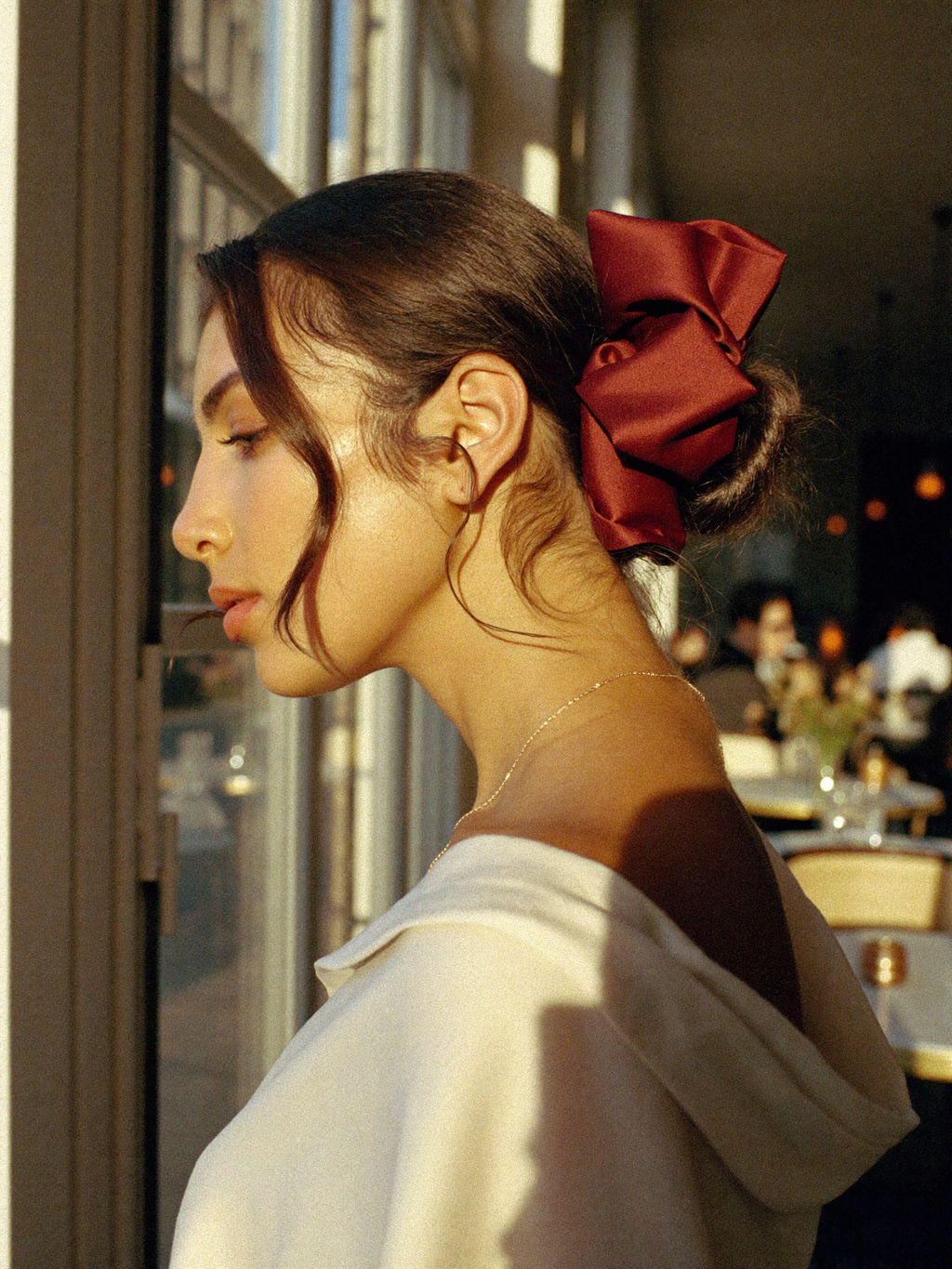 Woman wearing oversized burgundy French satin scrunchie in Paris café