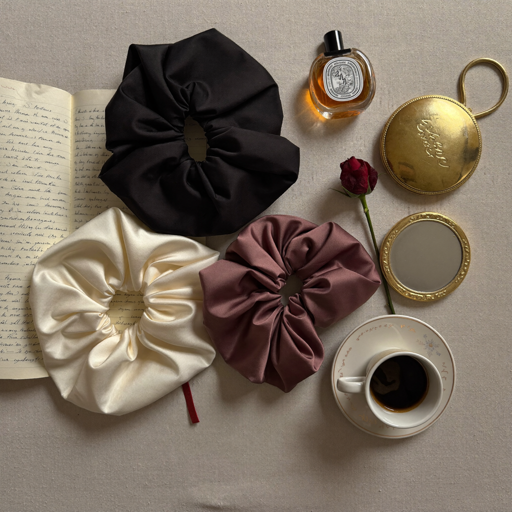 Le Chouchou satin scrunchies flatlay — black cream mauve editorial