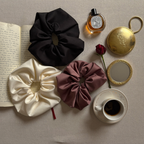 Le Chouchou satin scrunchies flatlay — black cream mauve editorial